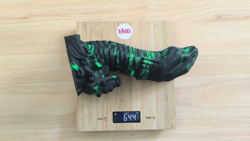 Na obrázku je monster dildo Lizard Peak od značky Beasty Cocks na stolní váze. Naměřená hmotnost dilda je 644g.